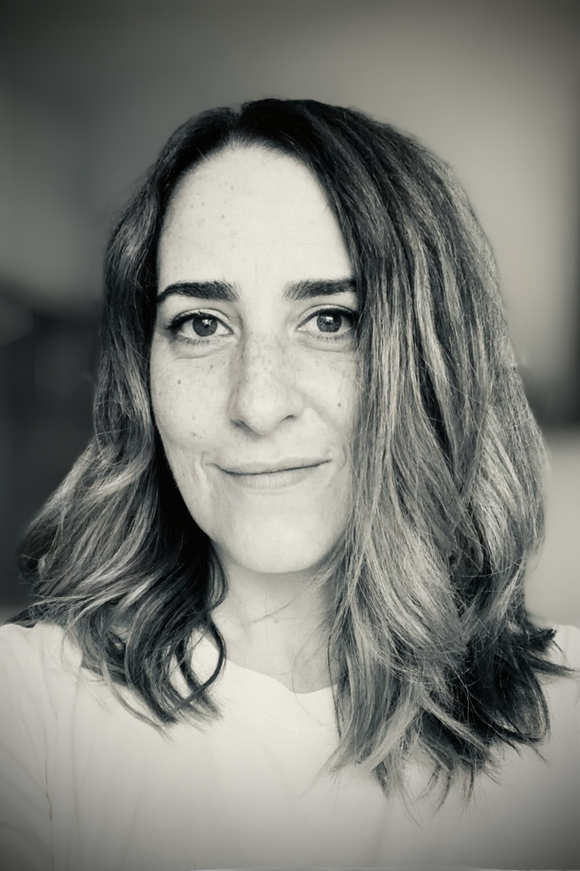 Un portrait en noir et blanc d'une femme avec des cheveux mi-longs ondulés, souriant légèrement.