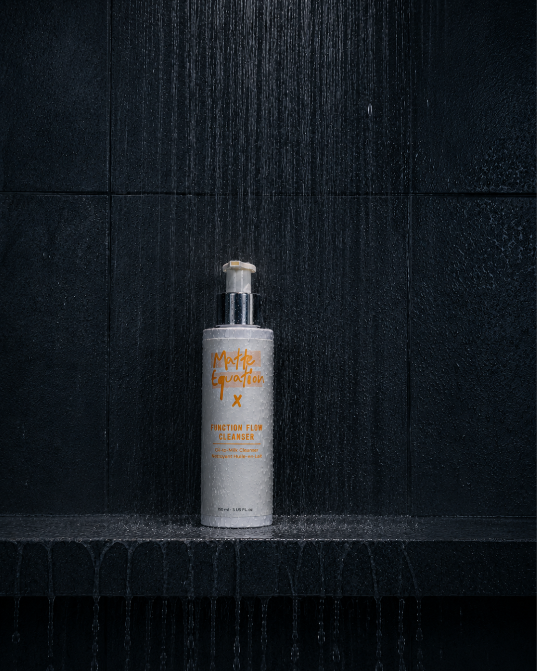 A white bottle of Matte Equation Function Flow Cleanser with orange text, placed on a wet black surface under a shower of water against a black tile background.