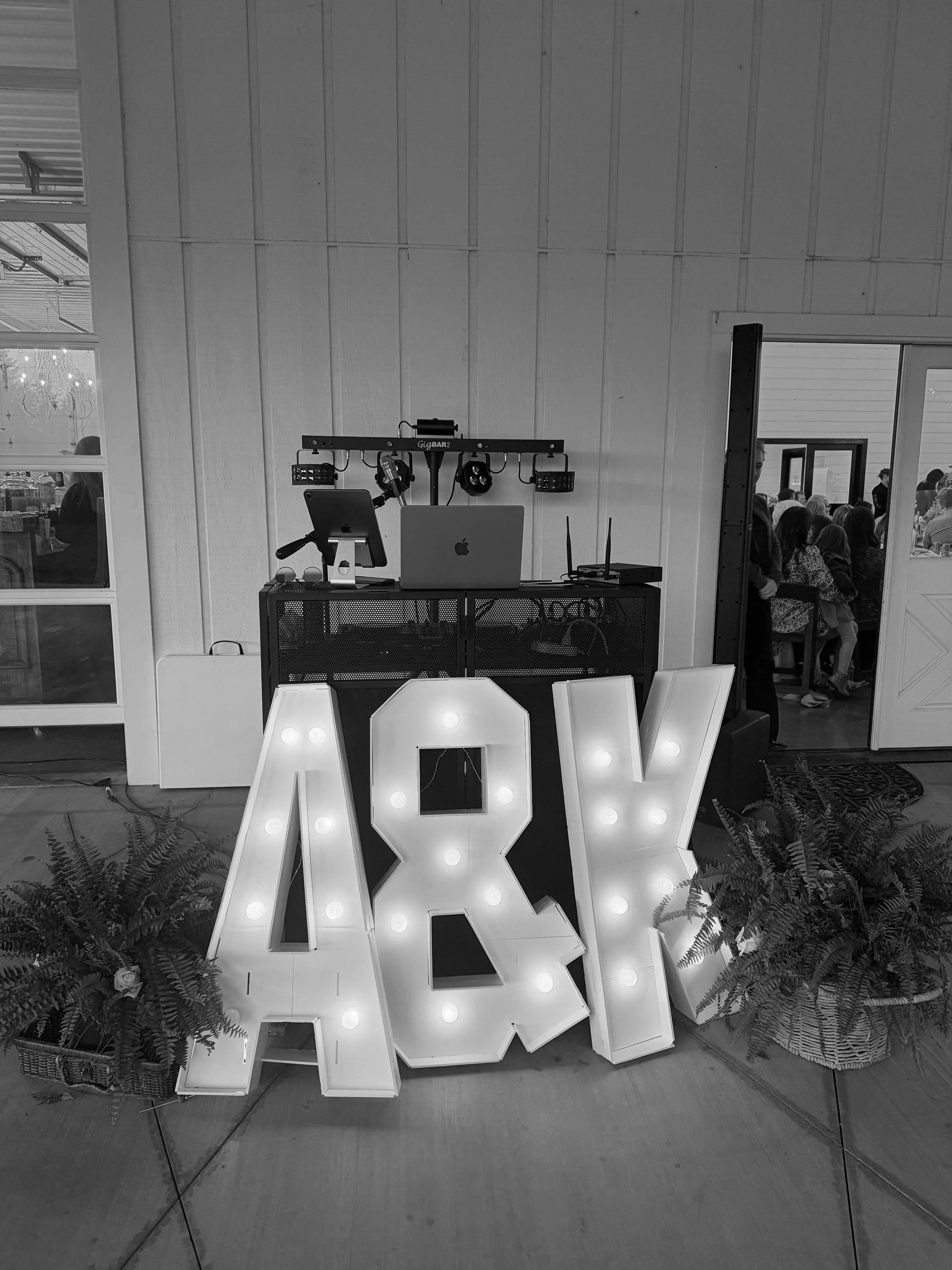 Decorative illuminated letters spelling 'LOVE' surrounded by plants at an indoor event.