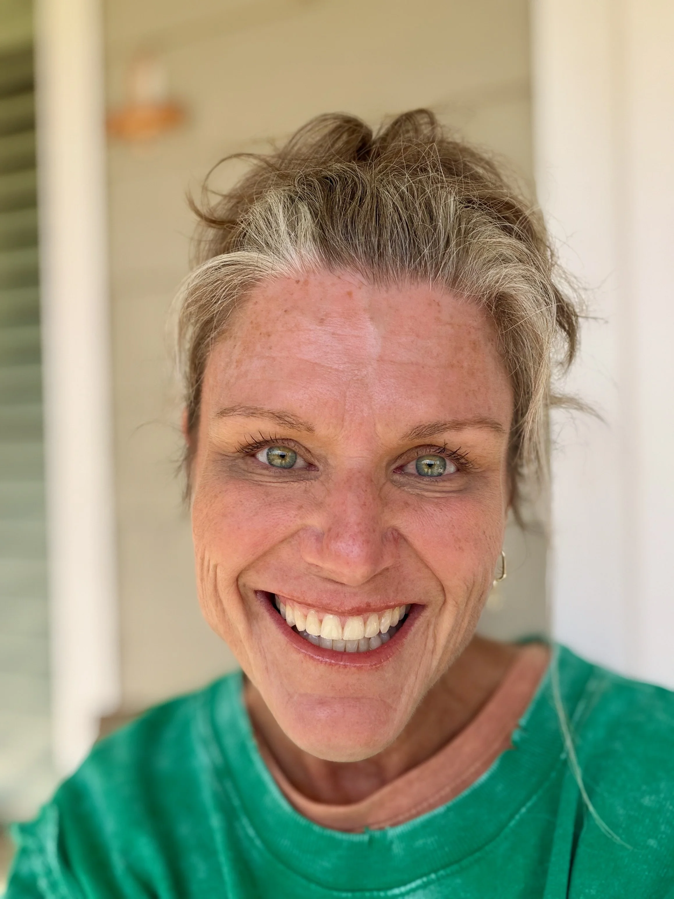 Julie smiling in a green top with natural silver-streaked hair for the Effortlessly Extra website.