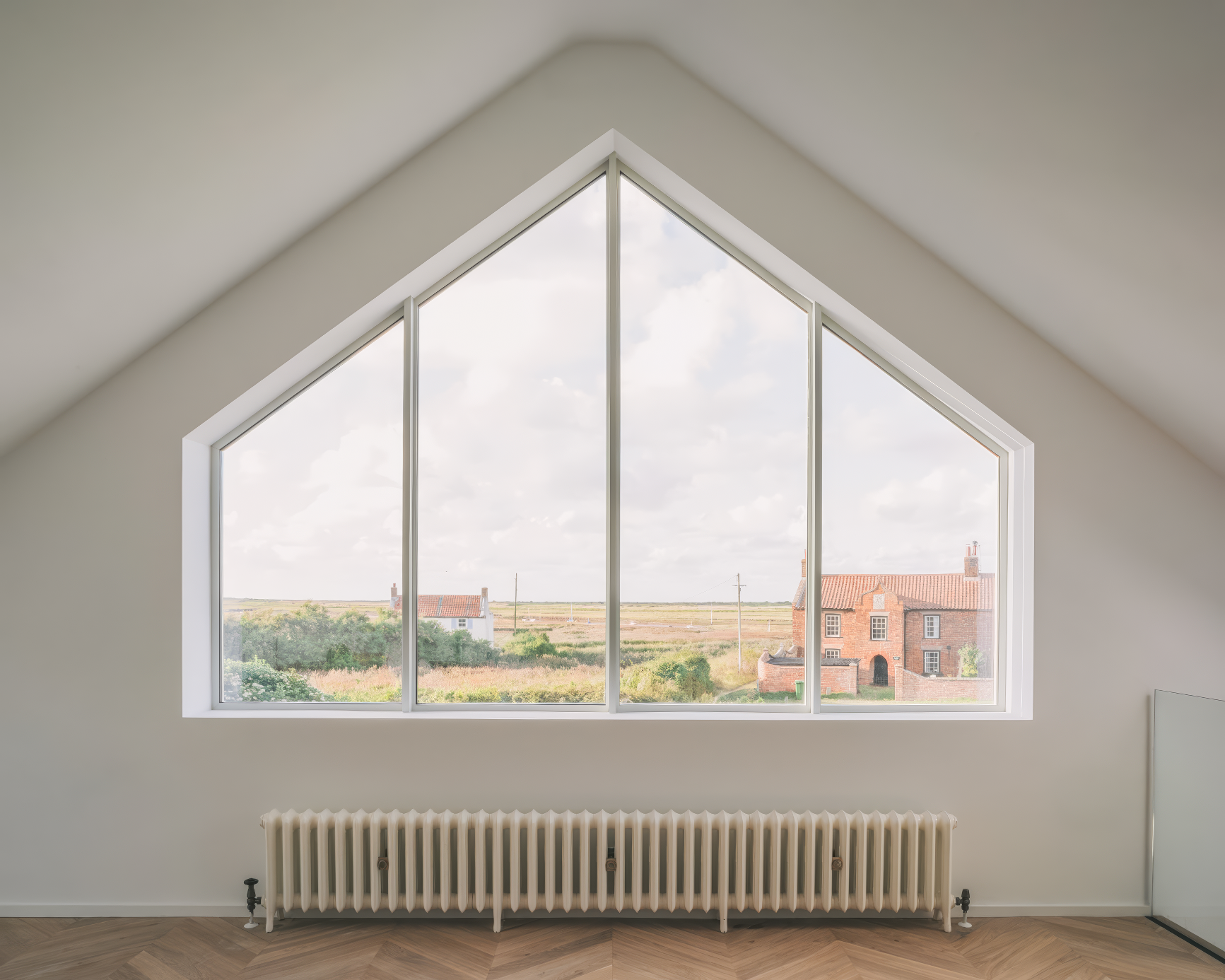 Scenic gable window view overlooking Norfolk countryside and cottages.