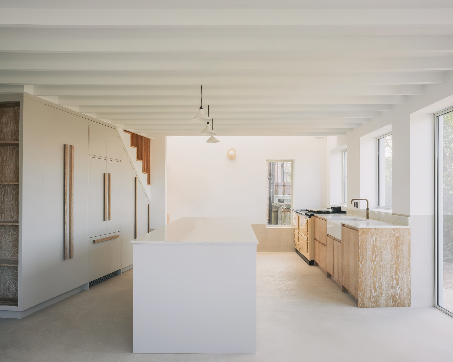 Clean-lined kitchen with white island, wood cabinetry, and Aga stove.