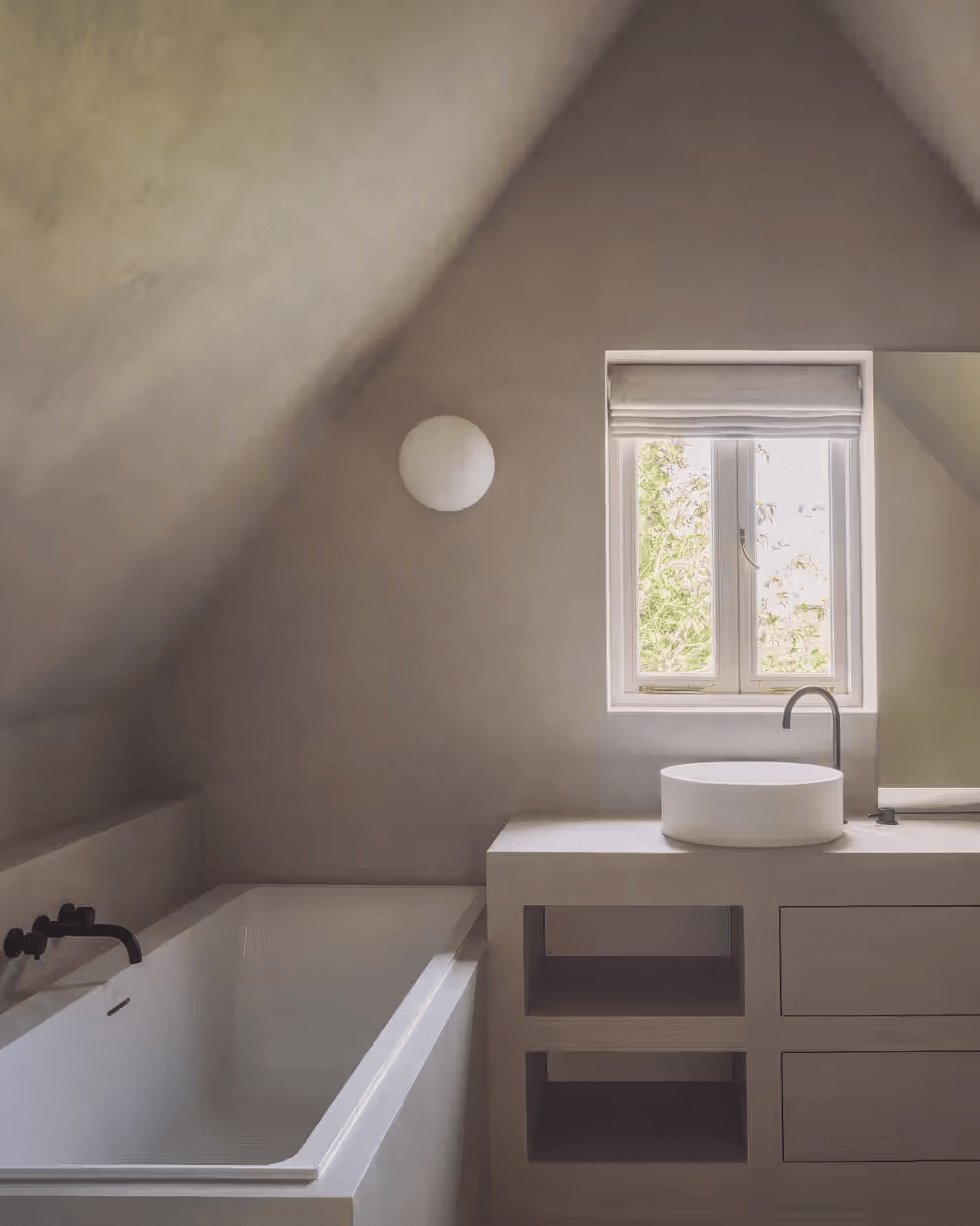 Contemporary bathroom under a pitched ceiling with textured plaster walls, a deep soaking tub, and a sculptural round sink basin.