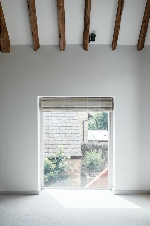 loft-bedroom-sloped-ceiling-exposed-beams-and-roman-blind-window.jpg