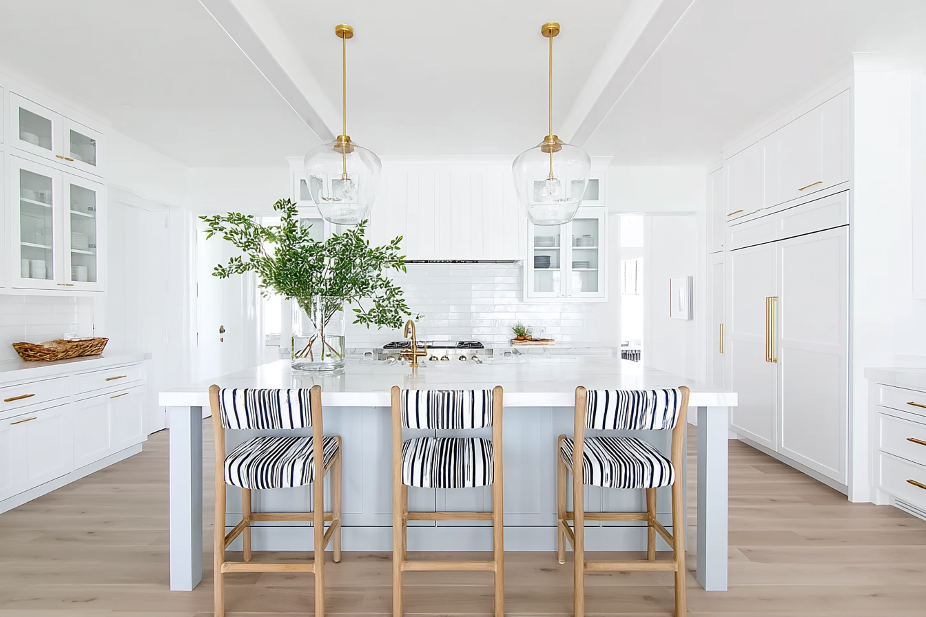 bright modern coastal kitchen interior white and soft blue island gold hardware accents pendant glass dome lights three natural wood bar stools