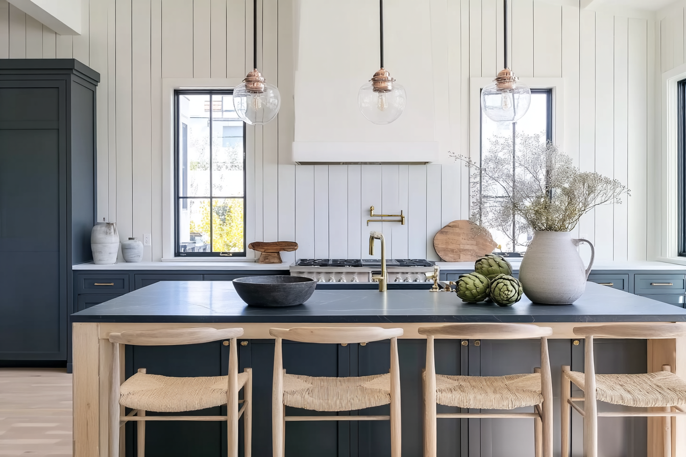 modern farmhouse kitchen interior matte navy blue lower cabinets island wood bar stools white wall paneling three pendant lights