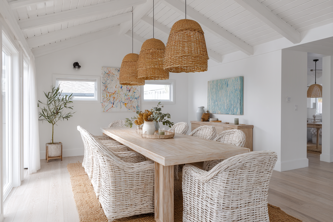 Serene contemporary coastal dining room featuring a lightwashed wood table, natural jute rug, and airy soft white palette for timeless beachside elegance