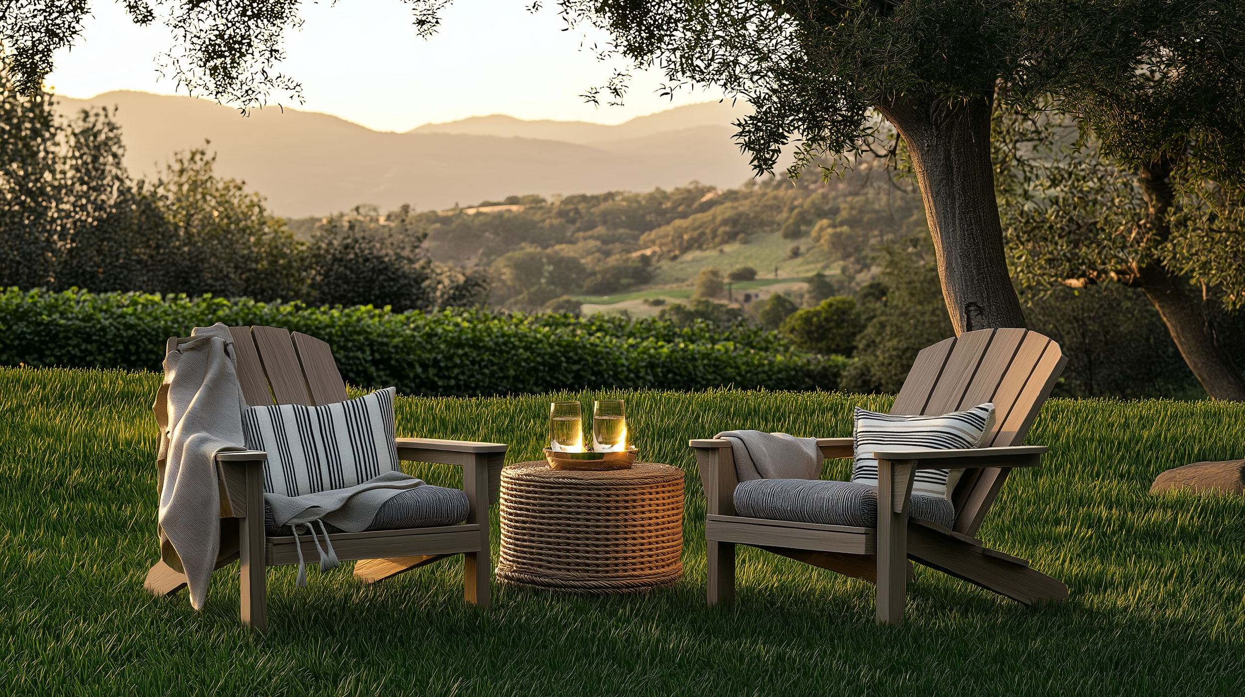 Golden hour outdoor retreat with two rustic Adirondack chairs made of weathered wood, placed on a lush green lawn overlooking a serene mountainous landscape.