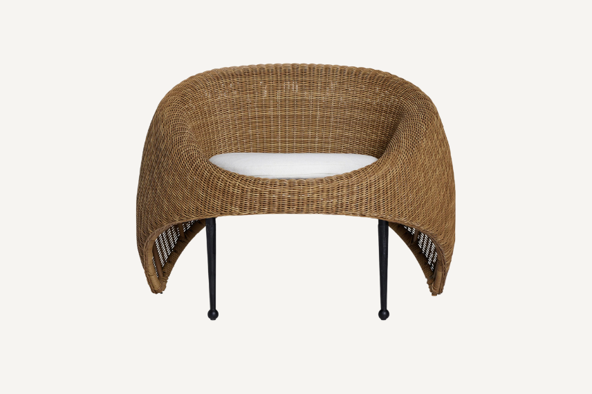 The Marisol wicker outdoor chair offers wicker seating reimagined with its egg cup sculptural form, black steel legs and its shape which is contoured for comfort. It's set against a neutral background.