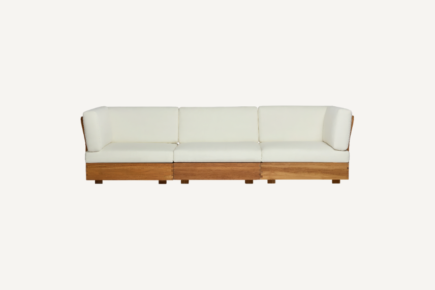 A modular sofa that features a detailed teak frame with plush, knife-edge cushions for a clean, comfortable look with a neutral background.