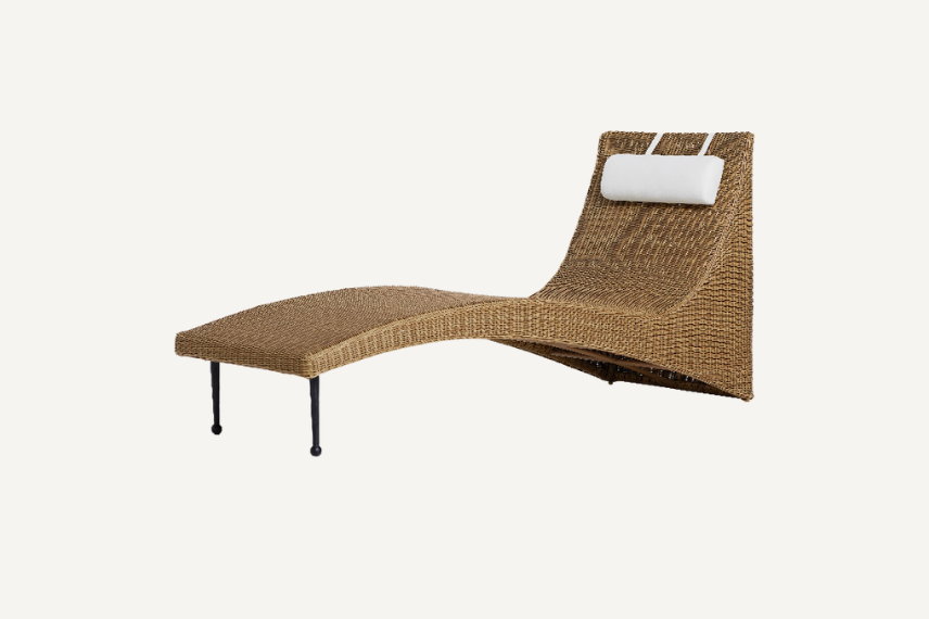 The Marisol outdoor chaise offers sculptural wicker seating, contoured for comfort. Perfect for outdoor living, this lounger has a pillow headrest and is set against a neutral background.