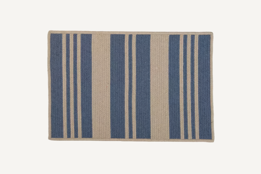 a stylish patio rug with Varsity Stripe braided reversible indoor outdoor rug set on a neutral background.