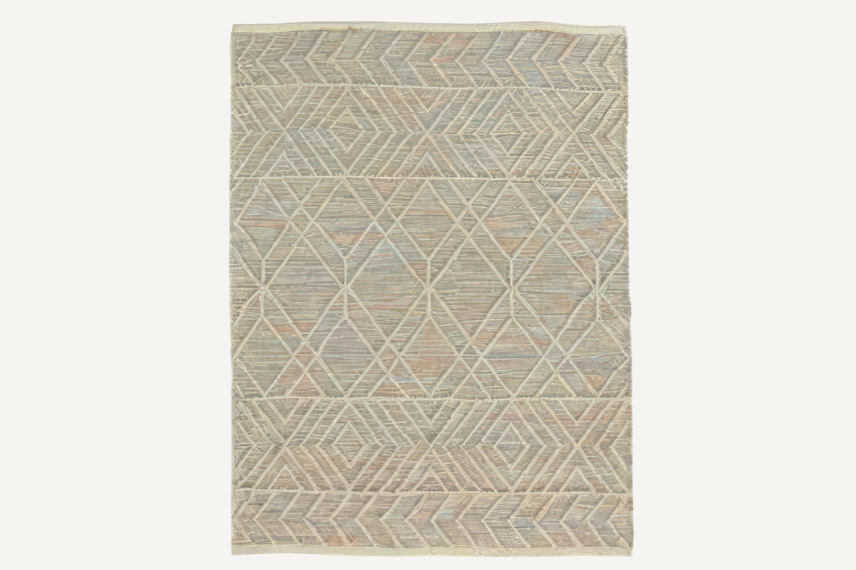Rectangular hand-woven outdoor rug featuring a subtle geometric pattern with diamond and chevron motifs in neutral tones. The textured weave and soft, earthy hues add warmth and depth to both indoor and outdoor spaces.