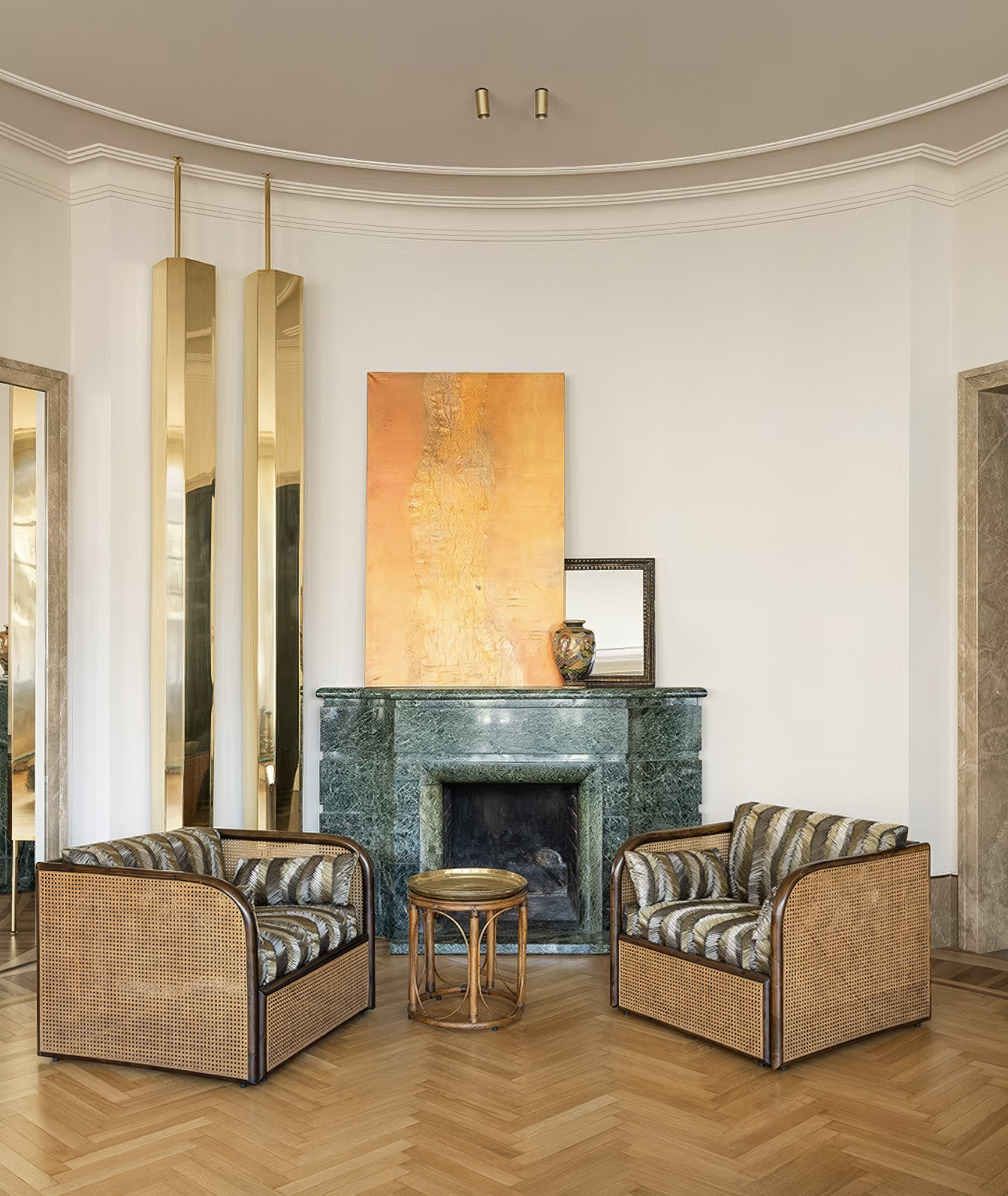 Cozy fireplace nook with twin rattan armchairs and green marble surround.