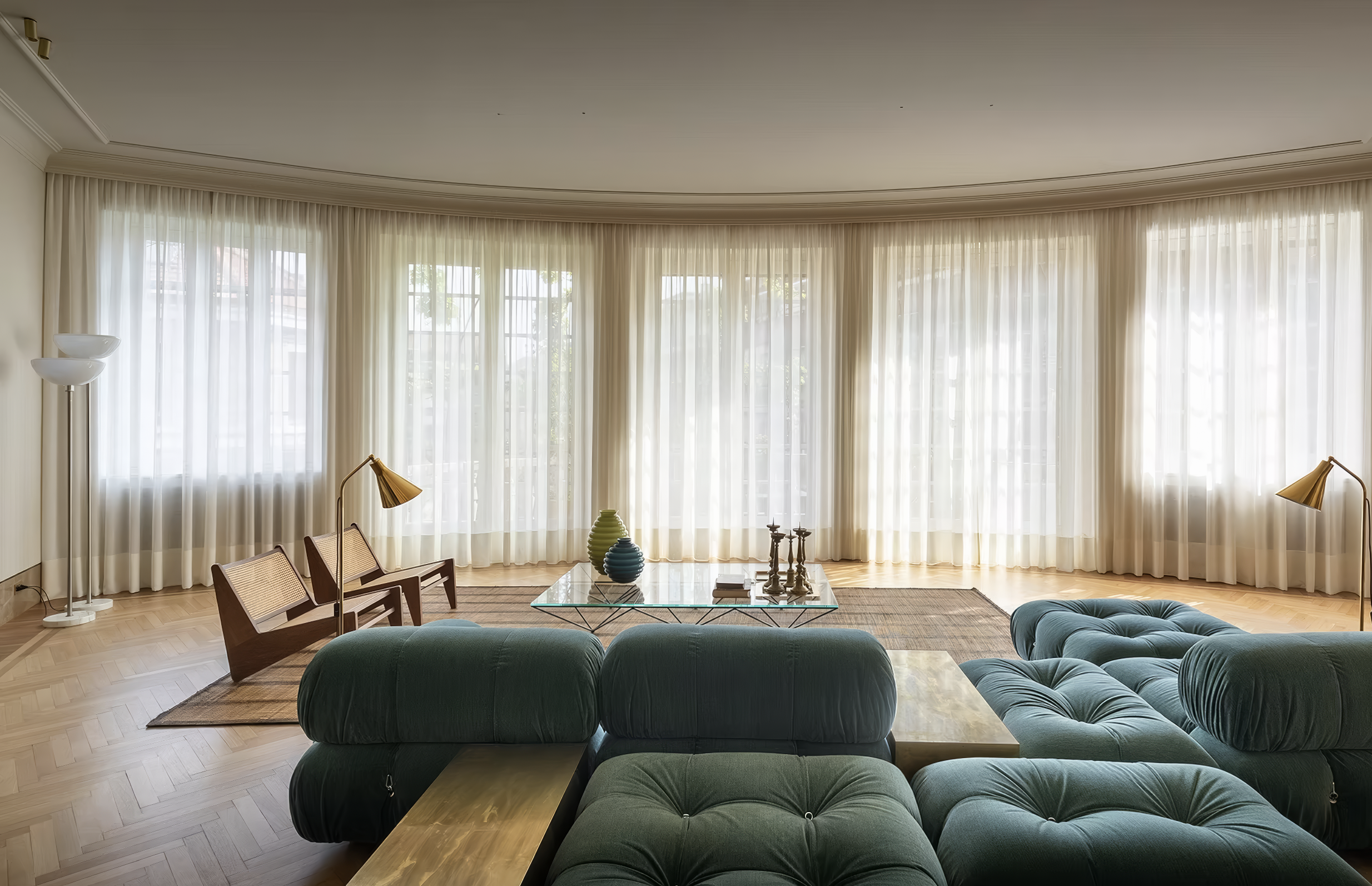 Floor-to-ceiling sheer curtains lining a curved window wall in a sunlit lounge.