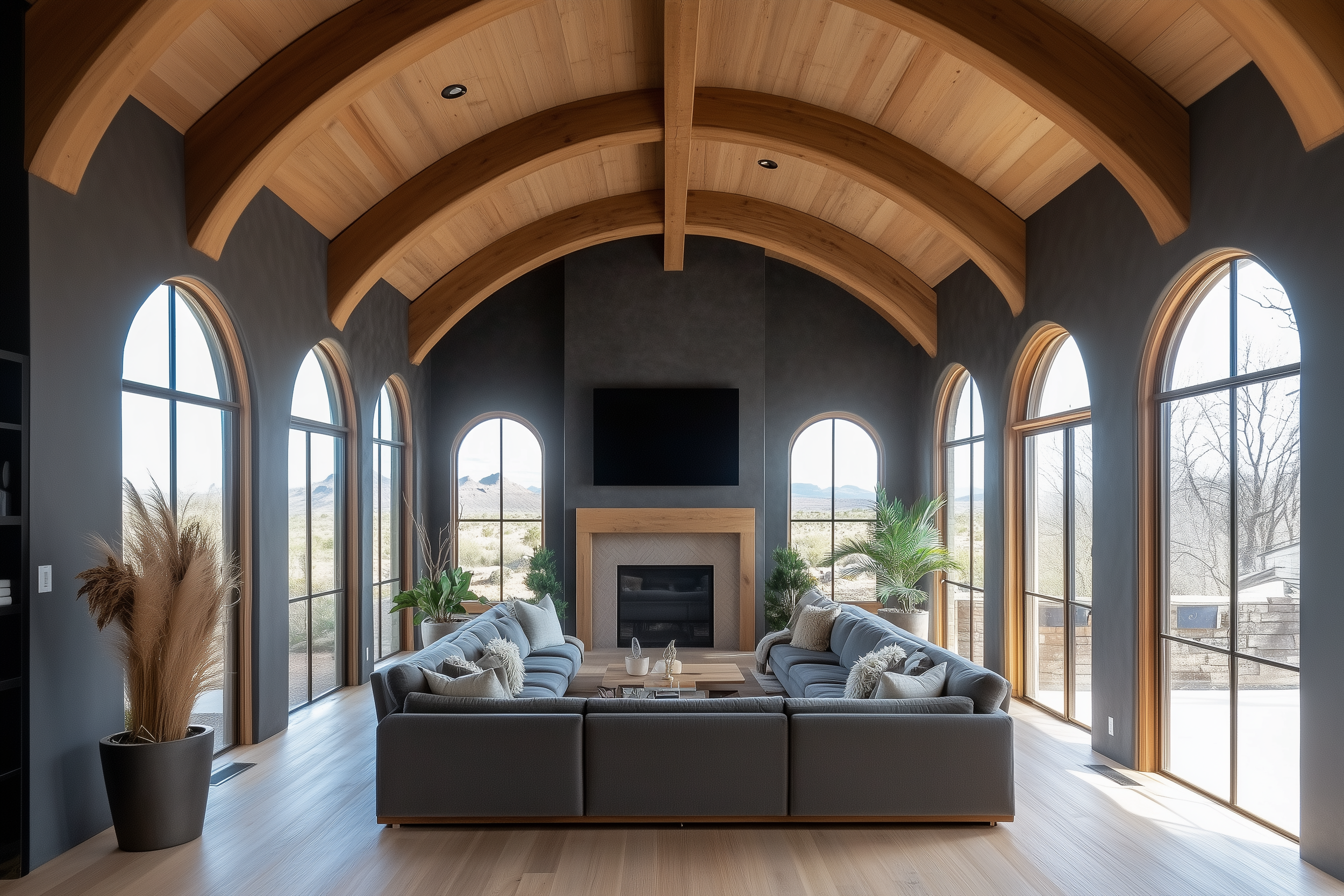 Modern barndominium living room with a dramatic barrel-vaulted wood ceiling, matte black walls, arched windows, and a spacious U-shaped sectional centered around a fireplace and TV.