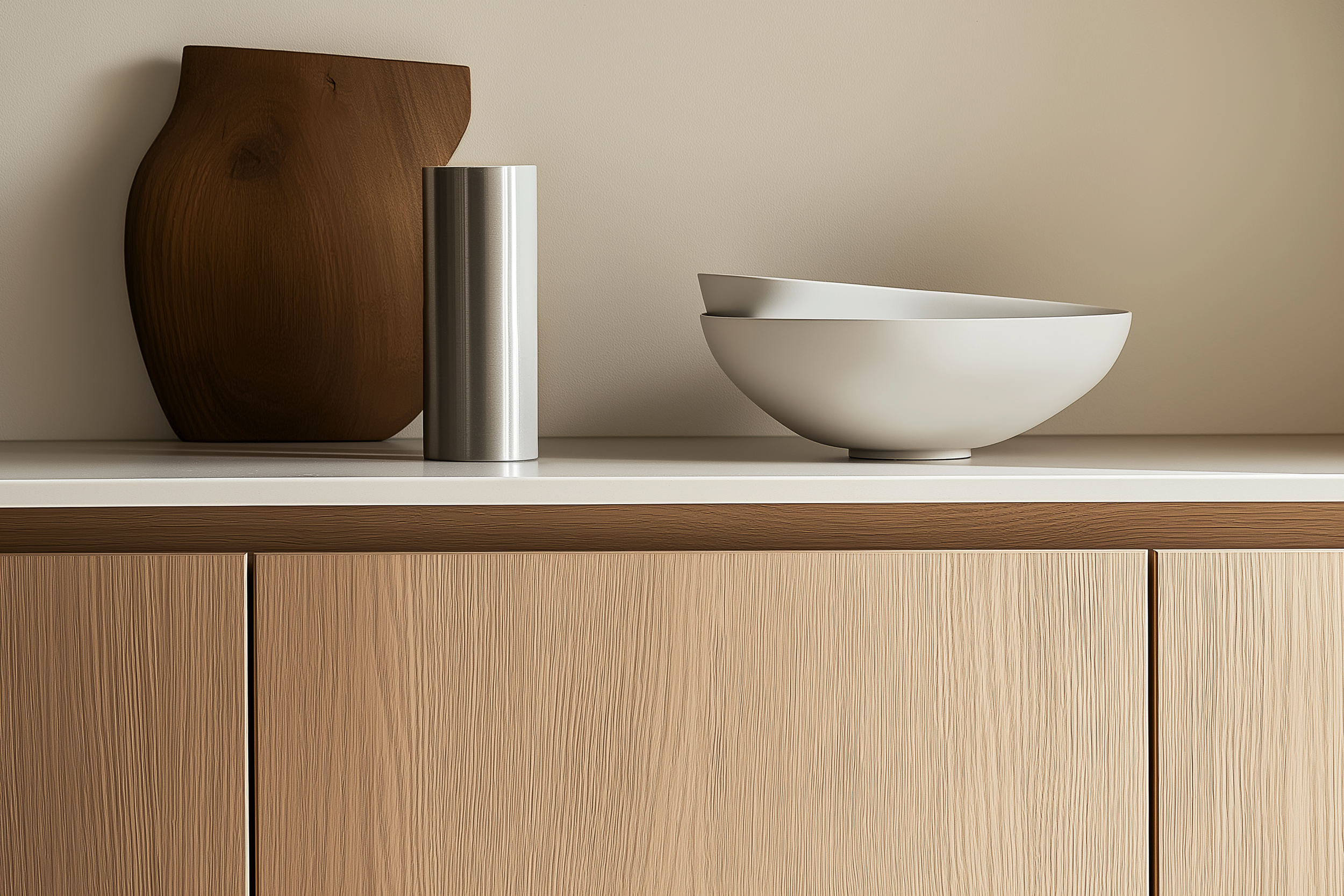 Close-up of a modern minimalist kitchen featuring light wood cabinetry, sleek surfaces, and decorative items like a black vase and simple bowls, highlighting the natural textures and clean lines of Scandinavian design.