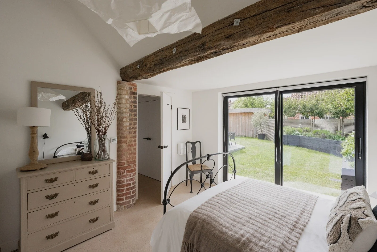 fen-barn-bedroom-exposed-beam-black-bed-frame-and-garden-view.jpg