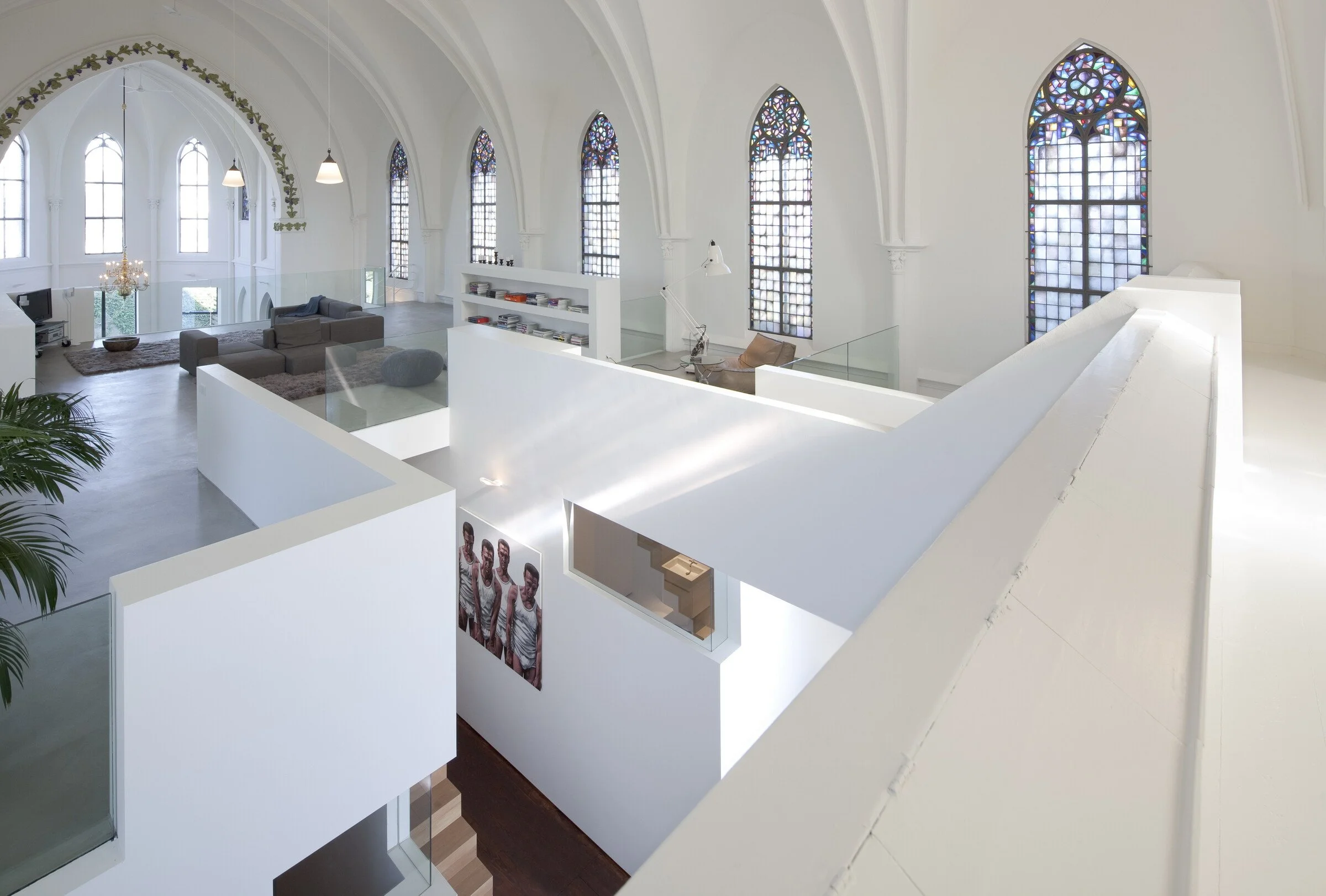 Floating white cube inside 19th-century church with stained glass and vaulted ceilings — modern design meets divine architecture.