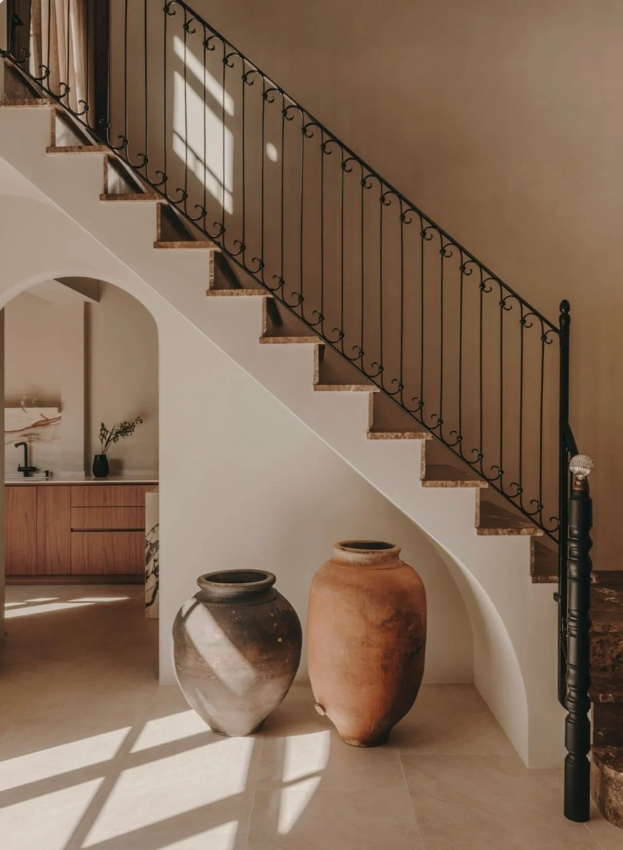 Two large rustic vases and a Spanish tiled flooring and staircase with wrought iron balustrade.