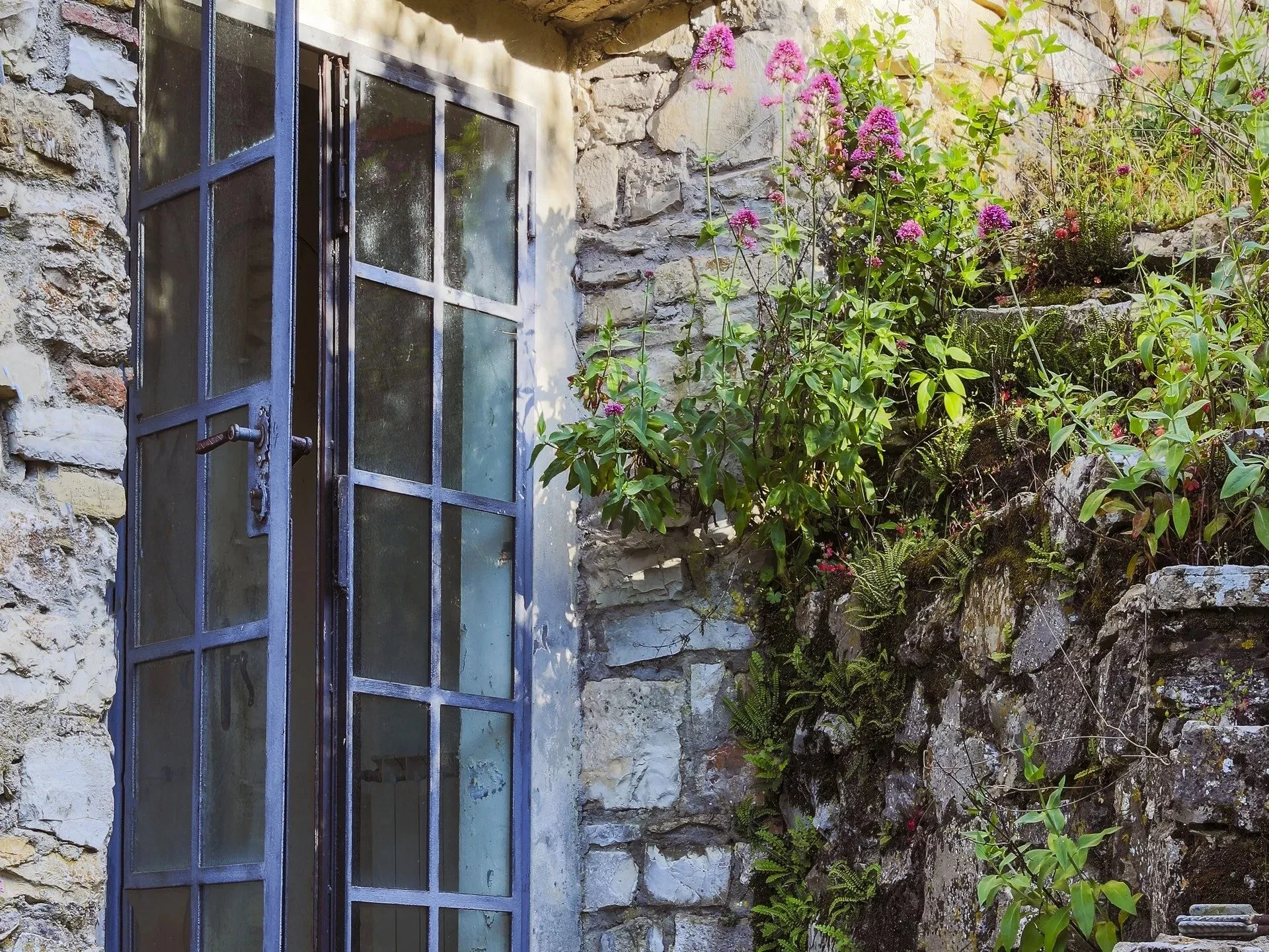glass-door-entrance-with-flowering-plants-in-tuscan-stone-house.jpg