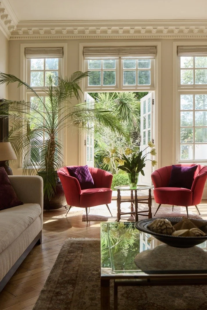 sunlit-garden-room-with-red-armchairs-and-palm-plants-overlooking-patio.jpg