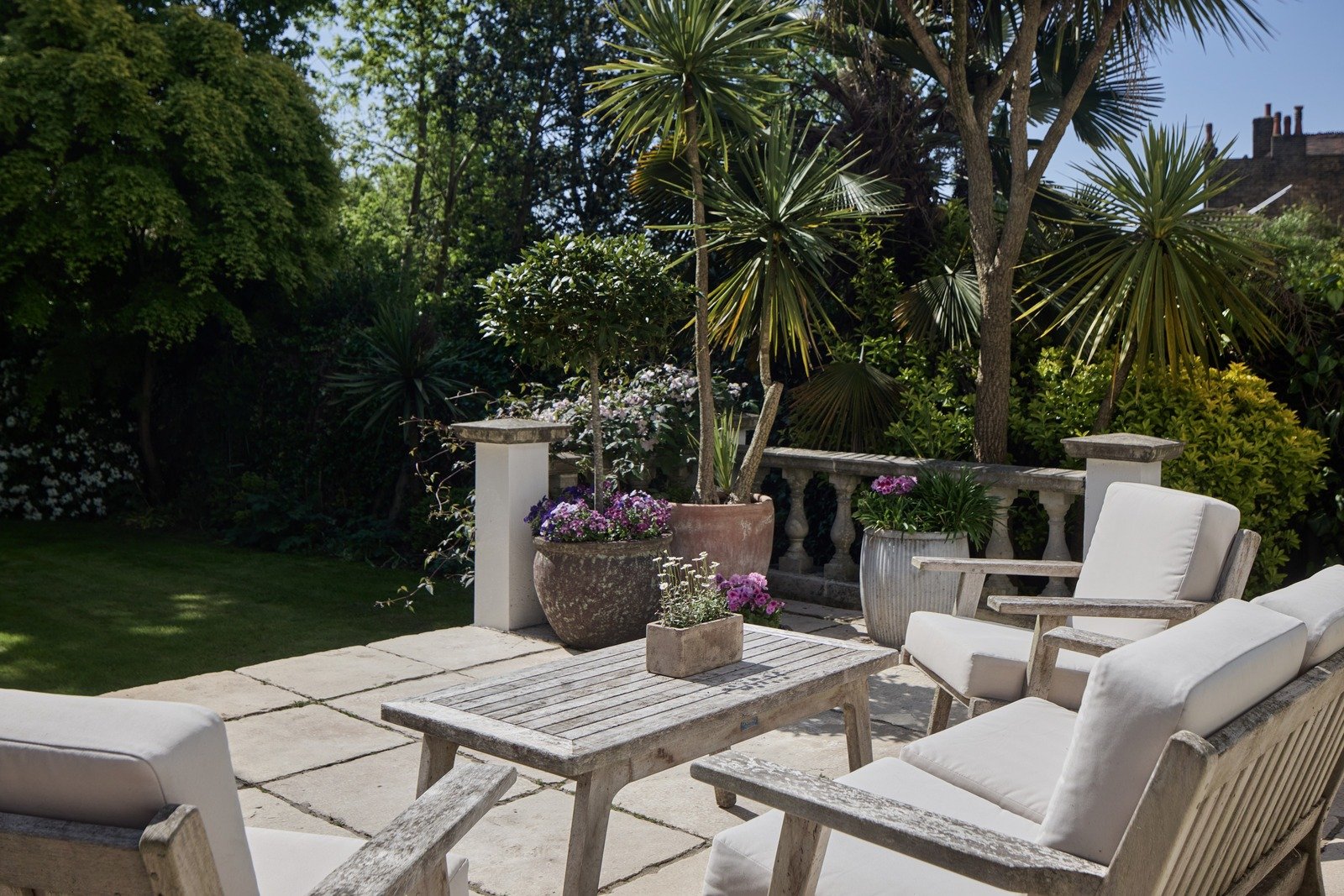 stone-patio-seating-area-with-weathered-wood-furniture-and-potted-palms.jpg
