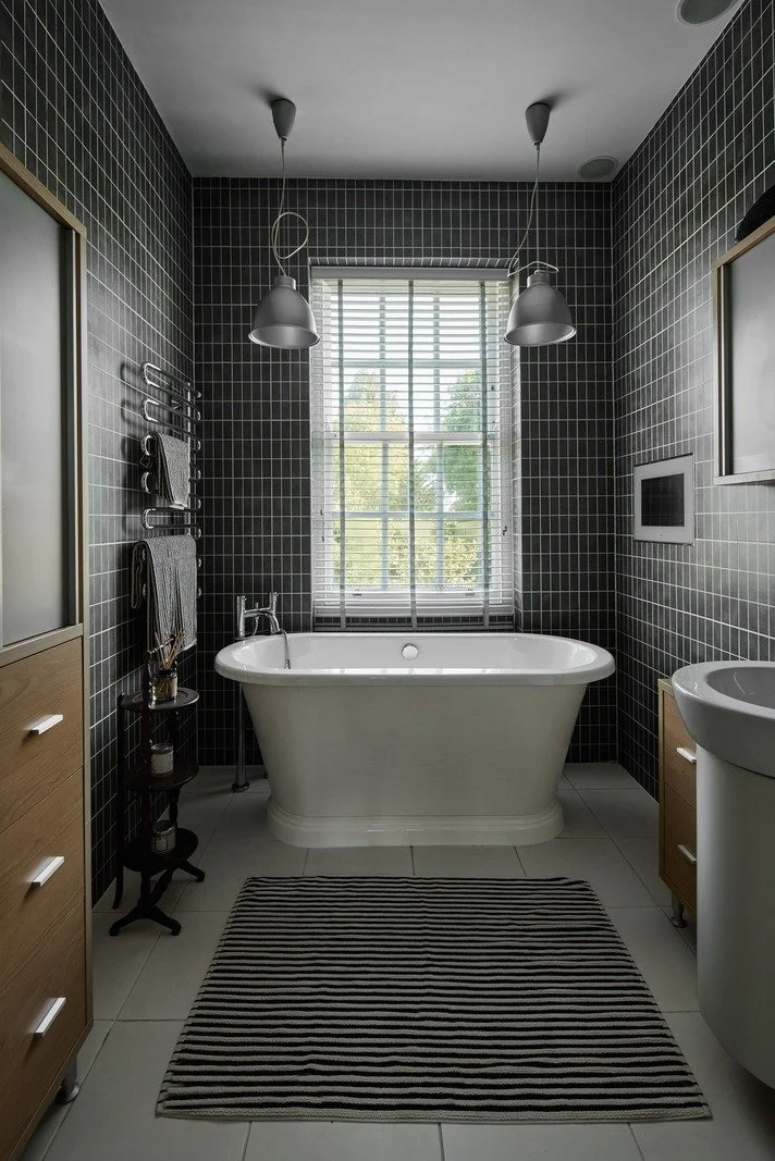 victorian-dark-tiled-bathroom-with-freestanding-bathtub-and-striped-rug.jpg
