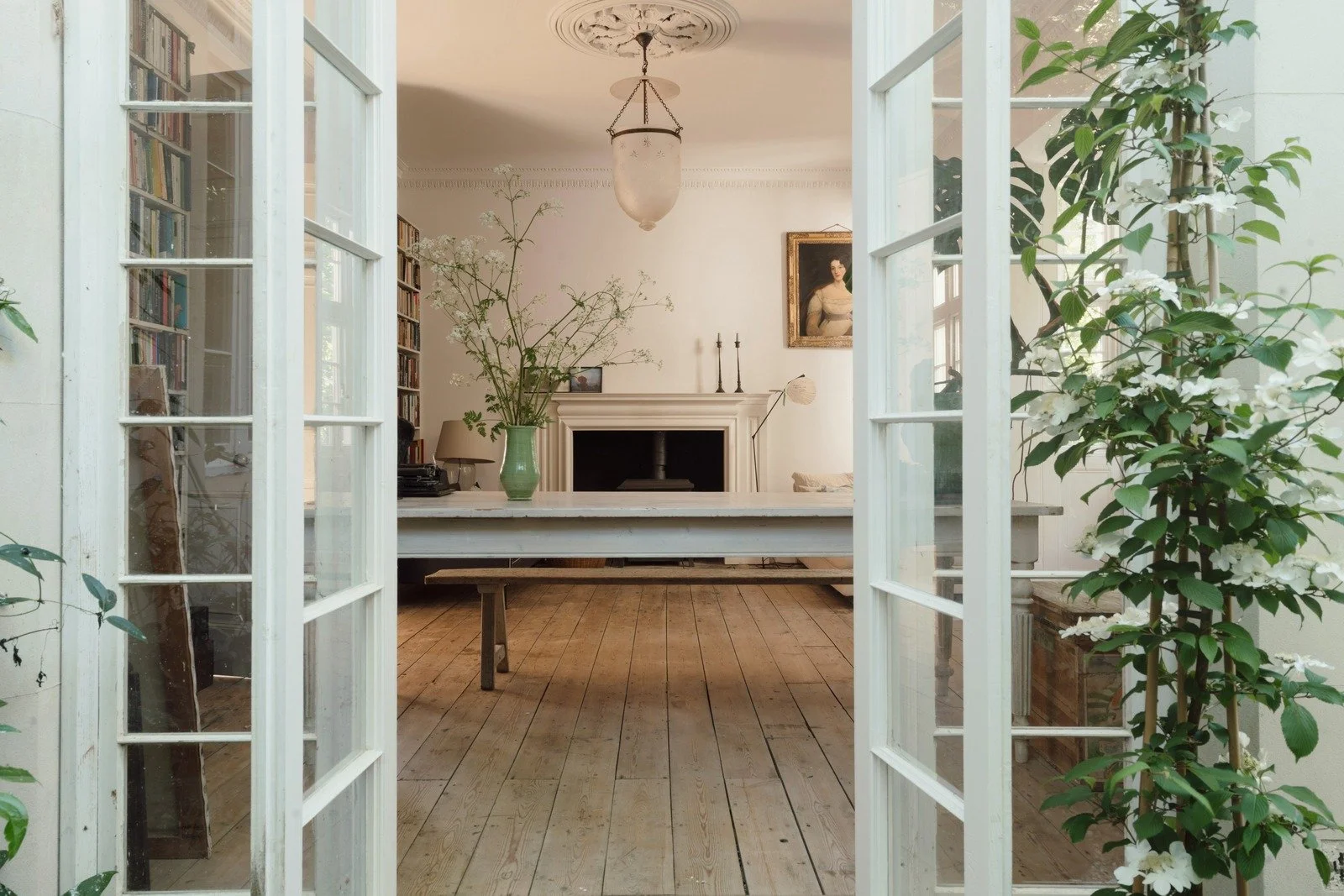 Reception room with floor-to-ceiling library to the left, fireplace in the center and French doors to the garden.