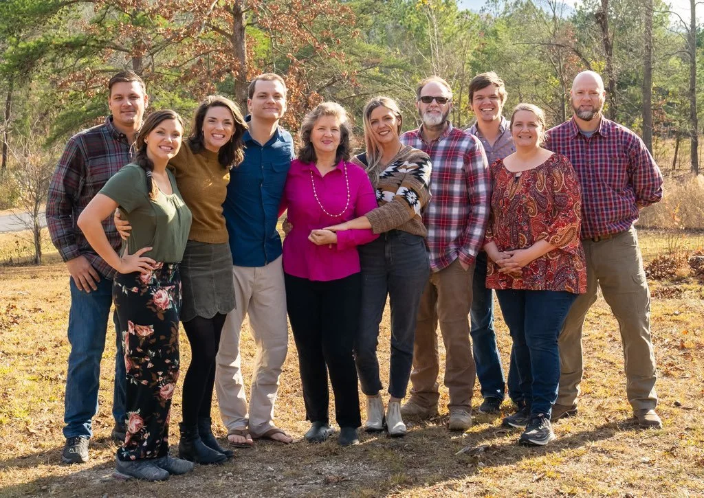 a woman and her nine  adult children posing happily for a picture