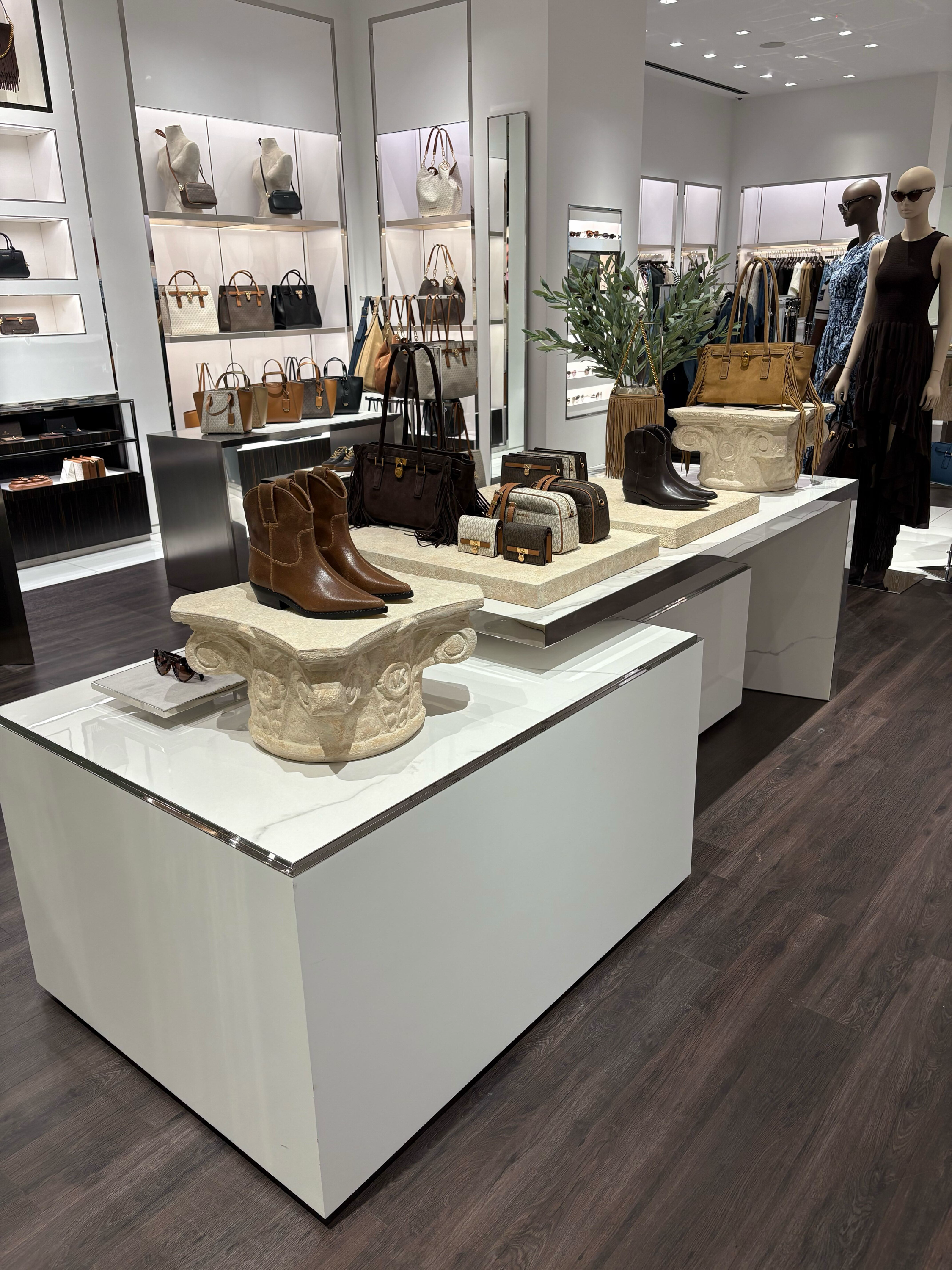 A retail store display featuring handbags, shoes, and sunglasses with mannequins dressed in clothing.
