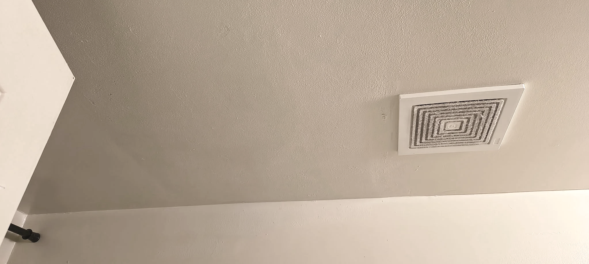 Ceiling vent in a room with beige walls and white ceiling.
