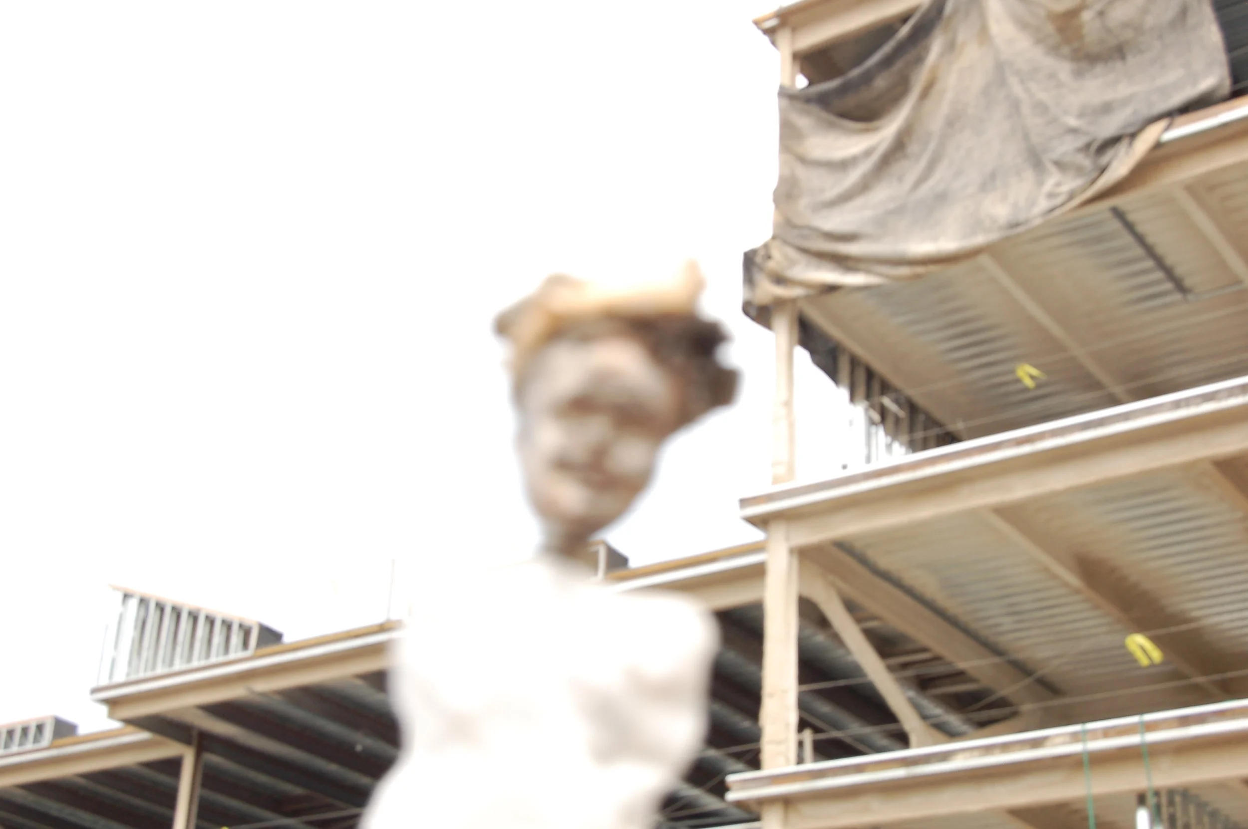 A scary-looking woman in white in front of a construction site with multiple floors under construction.