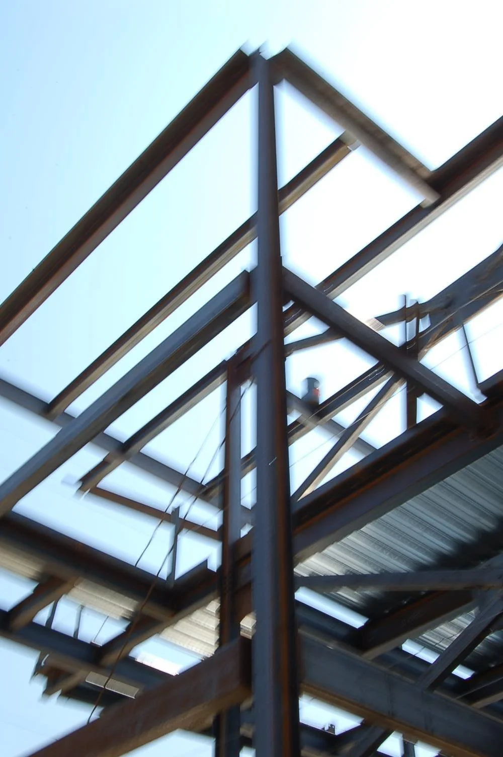 Construction building with steel beams and a partially completed framework viewed from below.