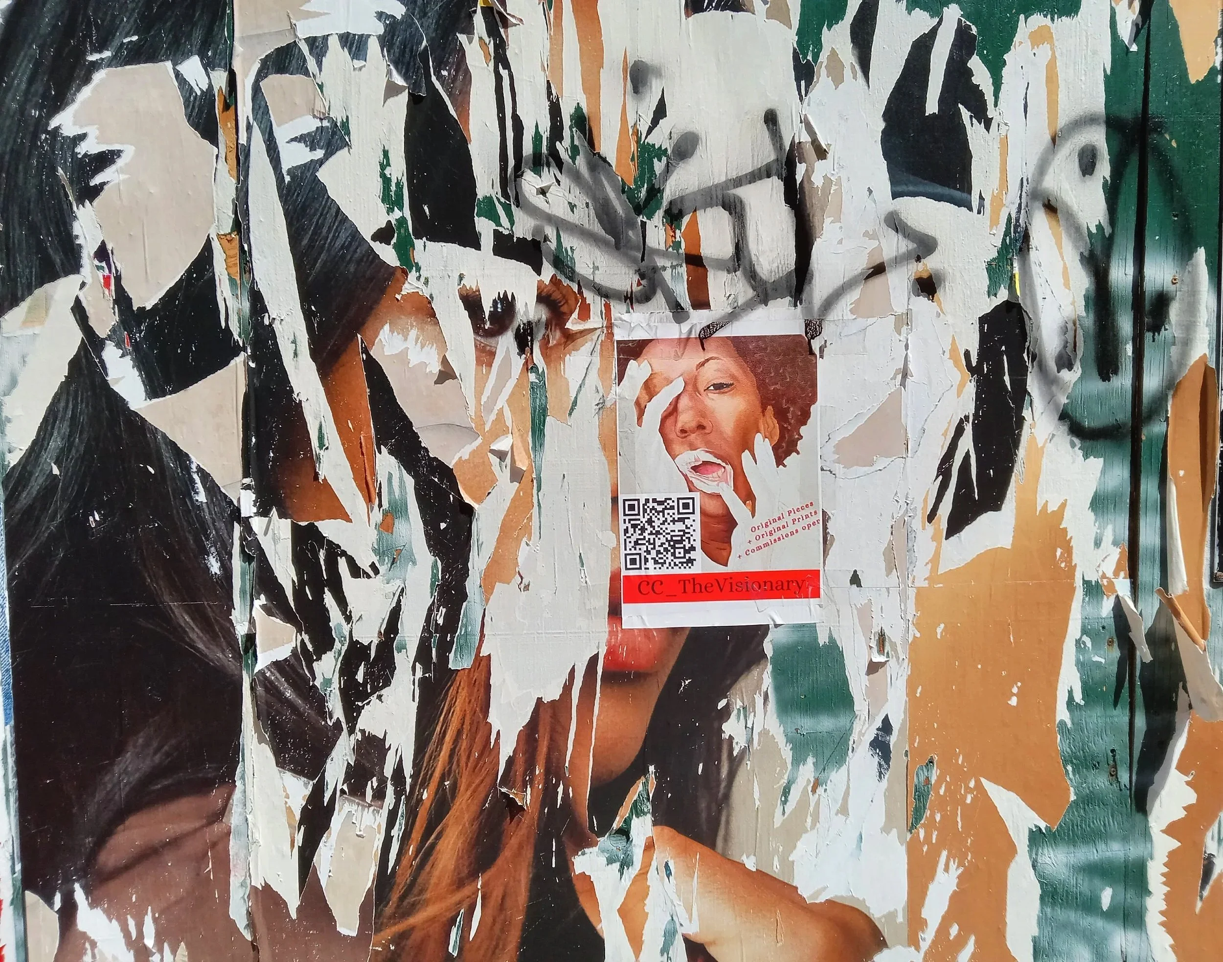 Close-up of a torn and layered collage poster featuring a woman with an expressive face, with various torn paper pieces creating a textured appearance.