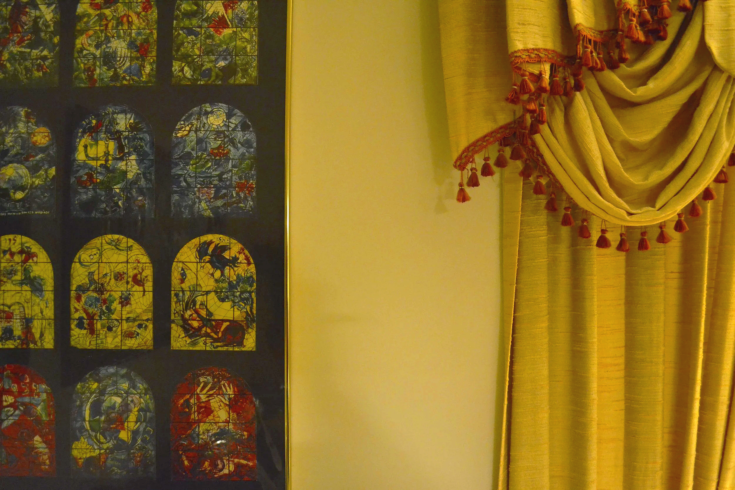 Framed artwork with colorful images and a yellow curtain with tassels.