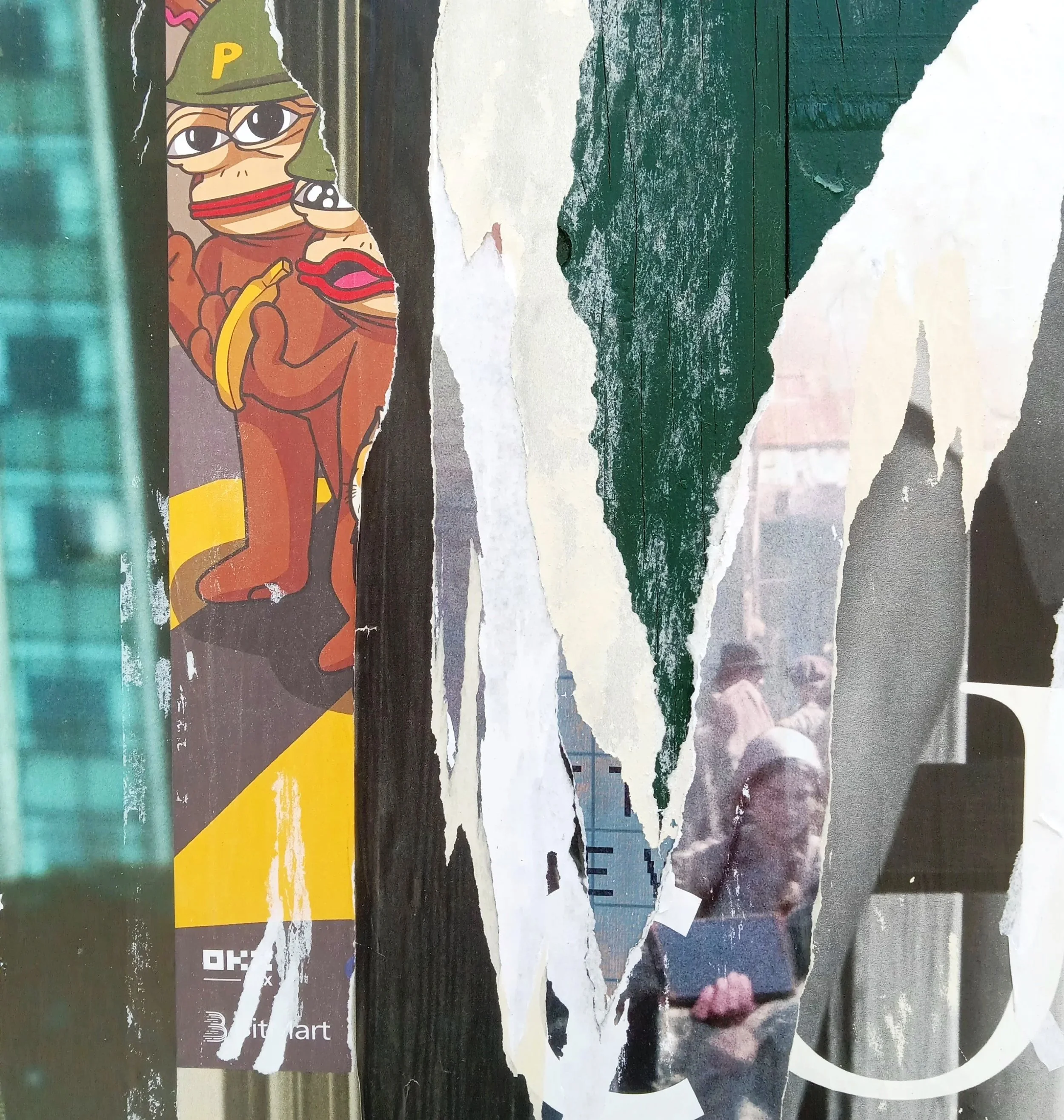 A torn piece of paper with a cartoon character of a monkey wearing a hat with a 'P' on it, holding a banana, and wearing an orange hoodie. The paper is pasted on a textured wooden surface with a green paint strip and a partially visible background.