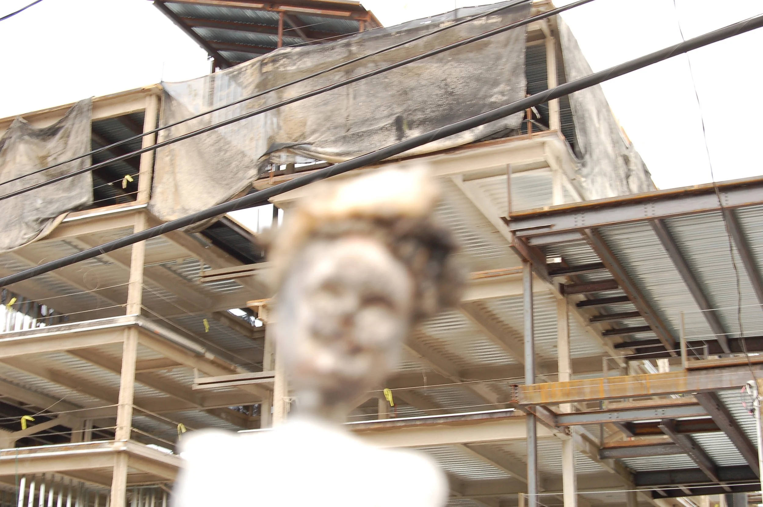 A construction site with multiple floors under development, featuring scaffolding and building materials. The photo is blurry with an indiscernible foreground object.