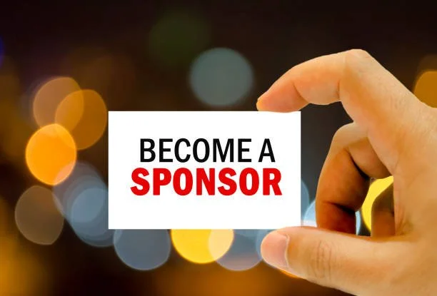 A hand holding a card with the text 'Become a Sponsor' against a background of blurry lights.