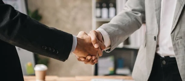 Two people shaking hands in a professional setting.