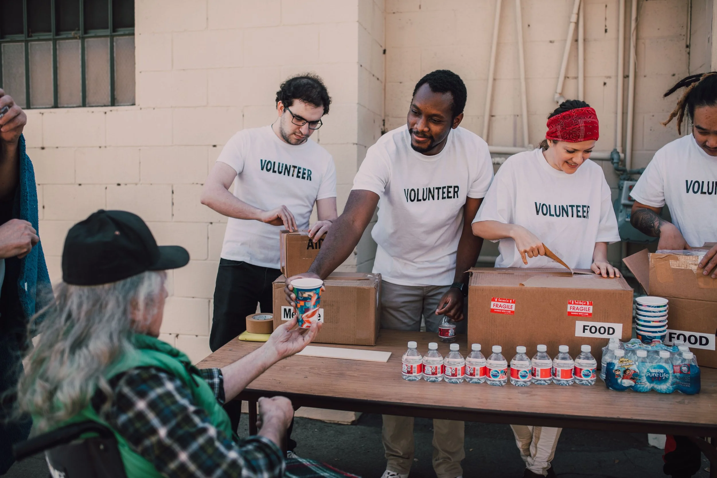 Group of volunteers serving food and supplies to people in need at an outdoor event.
