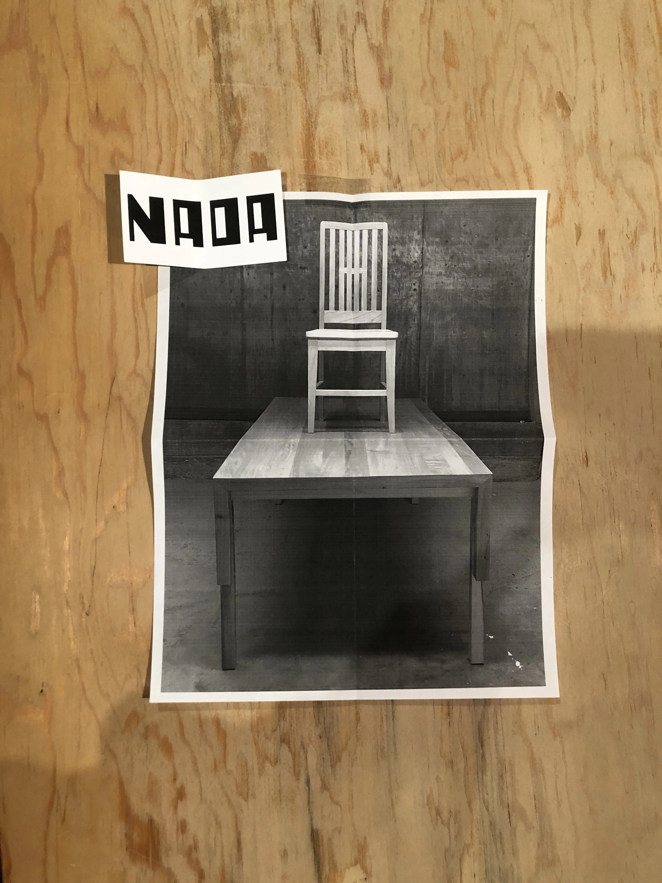 Fotografía en blanco y negro de una silla de madera en un fondo de paredes de madera y tapete en el suelo.