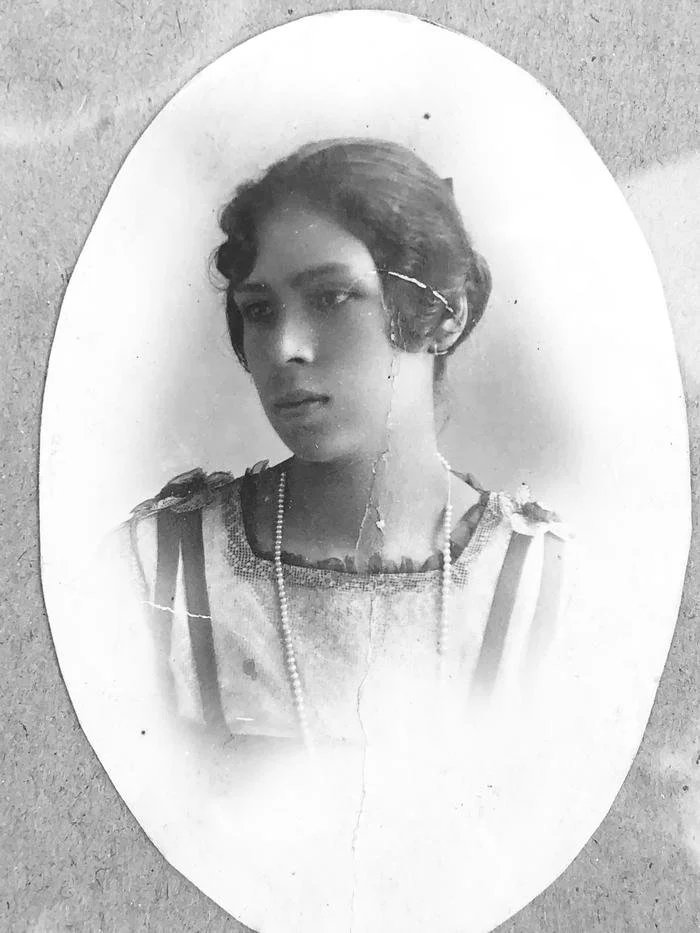 Retrato en blanco y negro de Victorina Juarez Lomelí, una mujer joven con corte de cabello corto, vestida con ropa elegante y un collar. La imagen está enmarcada con forma ovalada y muestra signos de envejecimiento y daños.