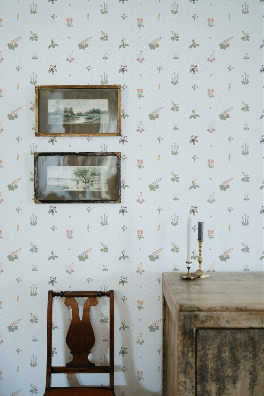 A vintage wooden chair and a rustic wooden chest with two candlesticks and candles, against a wallpapered wall with wildflower heirloom blue  lace Emily Maria Studios