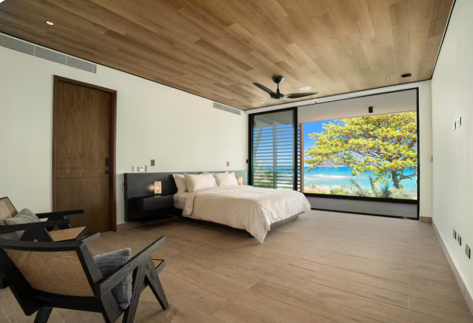 Minimalist bedroom with white bedding, ceiling fan, and navy accent bench at a kosher luxury villa, Dominican Republic