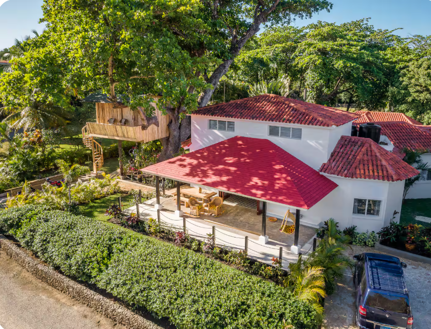 Aerial view of a red-roofed kosher luxury villa with lush garden and covered outdoor pavilion, Dominican Republic