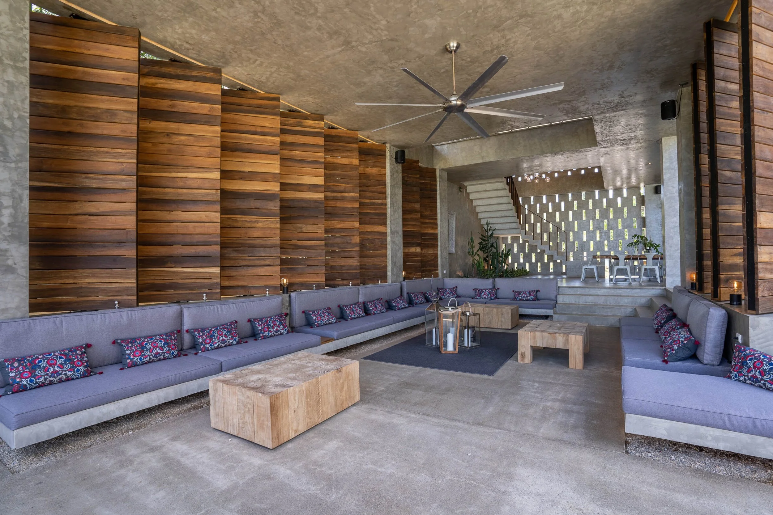 Covered outdoor lounge with wooden slat walls, blue sofas, and stone flooring at a kosher luxury villa, Dominican Republic