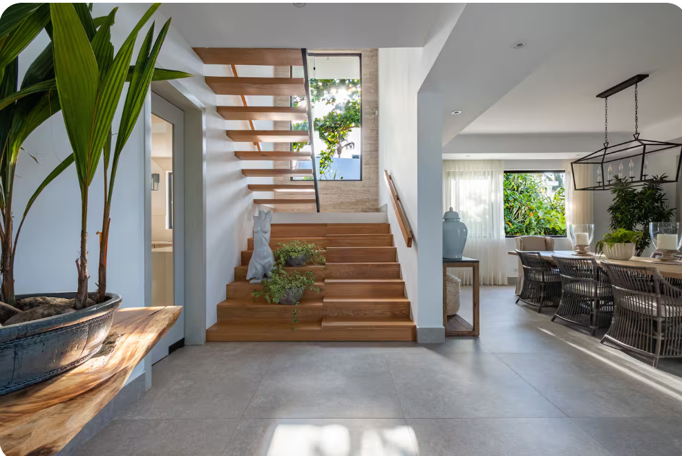 Luxury private villa interior with a modern staircase, tropical plants, and elegant open-plan living space in the Dominican Republic.