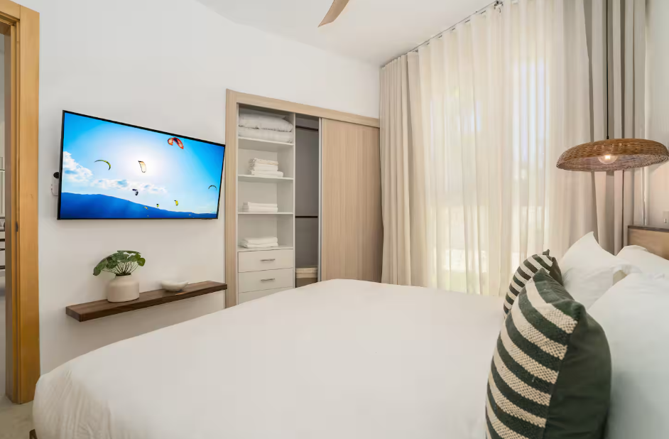 Modern bedroom with wall-mounted TV, built-in closet, and balcony access at a kosher luxury villa, Dominican Republic
