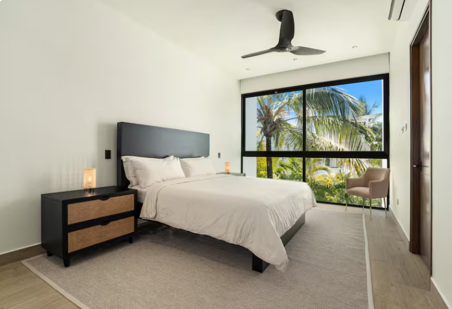 Minimalist bedroom with white bedding, ceiling fan, and navy accent bench at a kosher luxury villa, Dominican Republic
